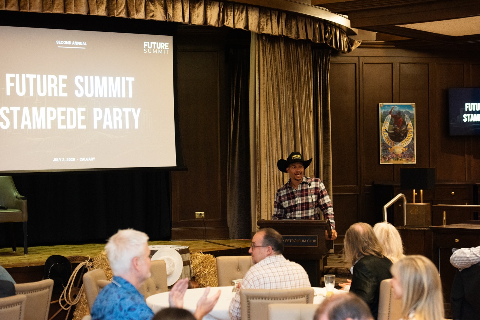 Josh Rainbow at the podium addressing a seated audience at the second annual Future Summit Stampede Party